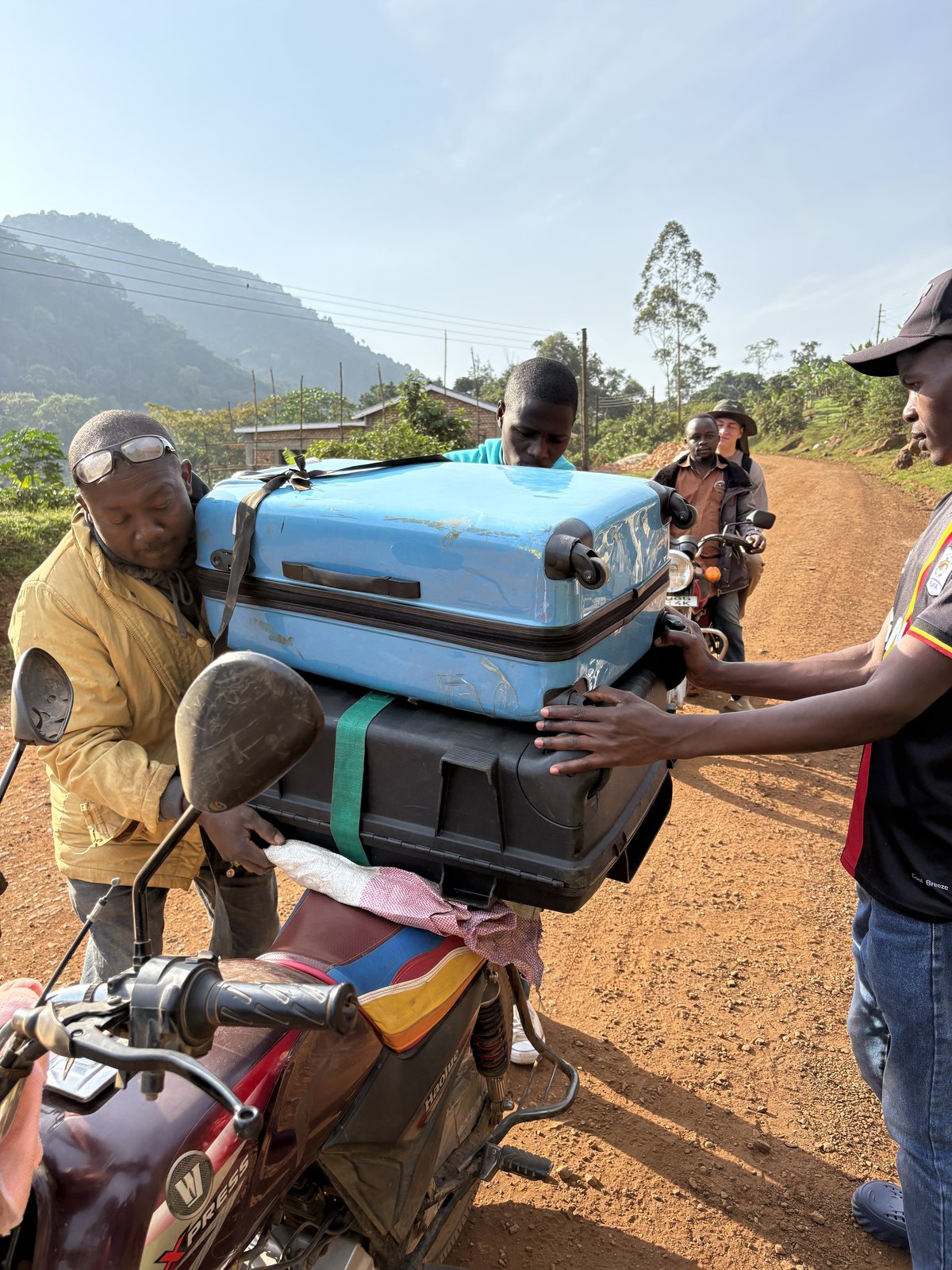 BodaBoda motorcycle loaded with suitcases on a red dirt road near Bwindi, Uganda