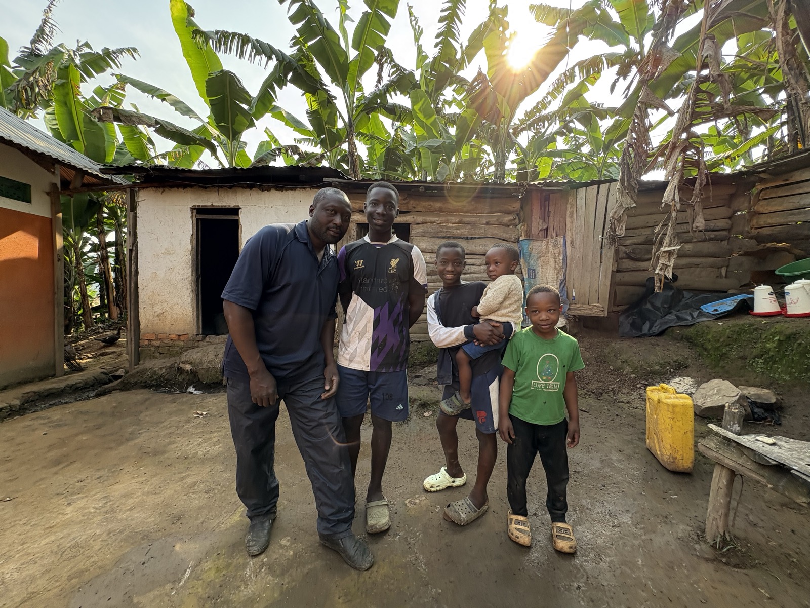 Chicken farmer with children in front of his farm in Buhoma village near Bwindi, Uganda